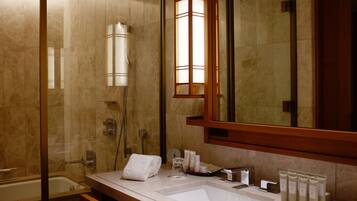 A modern bathroom with a glass-enclosed shower, a large mirror, a sink with toiletries, and a towel rack.