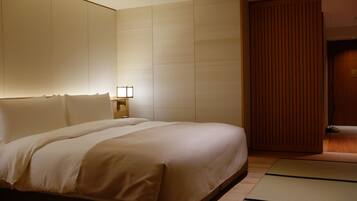 A hotel room with a large bed, a wooden wardrobe, and a nightstand with a lamp.