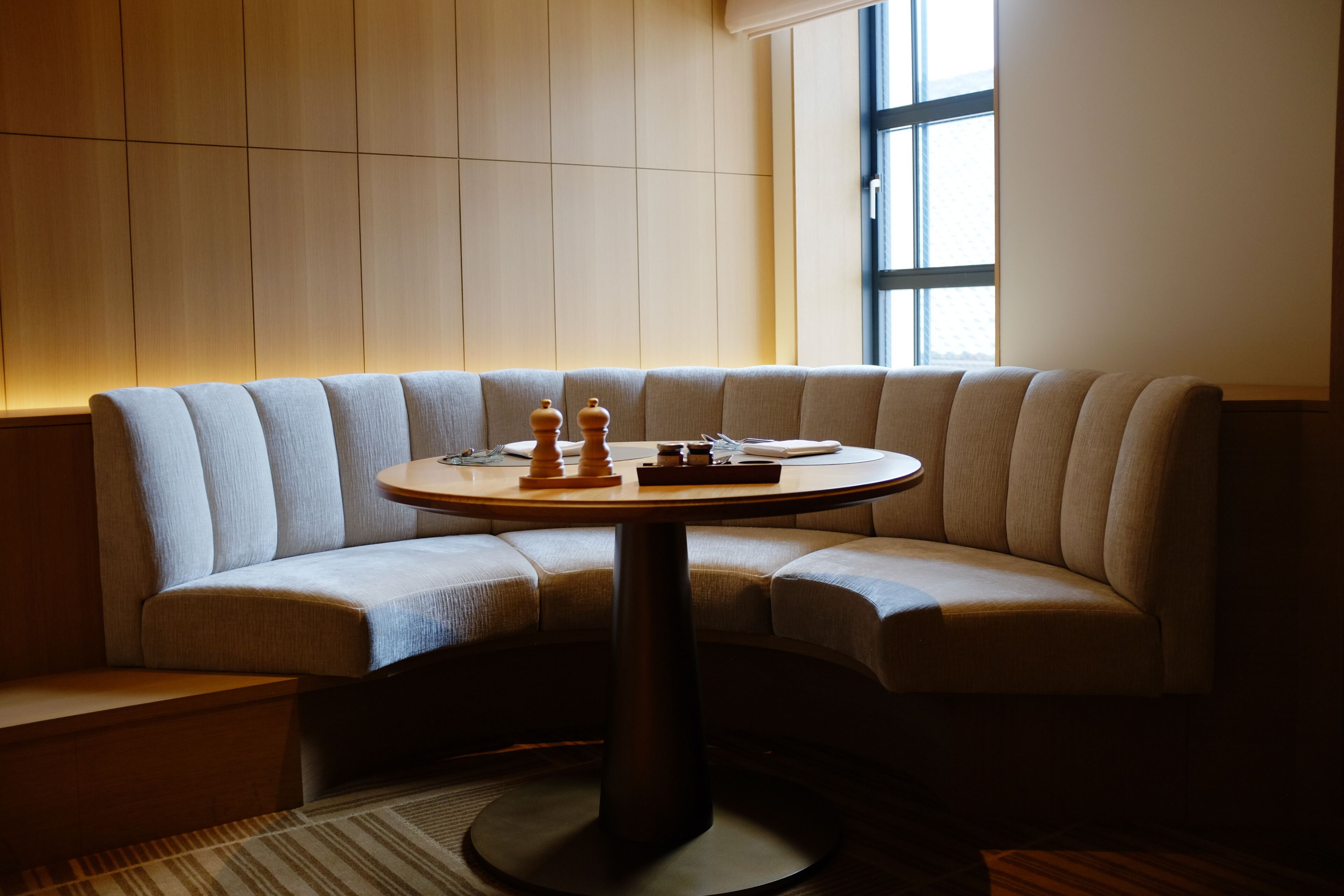 A modern room with a curved sofa, a round table, and a large window.