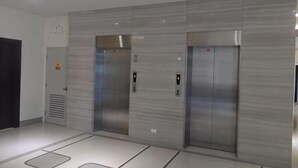 Un área de ascensores moderna con dos ascensores, un panel de control y un detector de incendios.