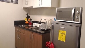 Una cocina pequeña con microondas, refrigerador y armarios de madera.
