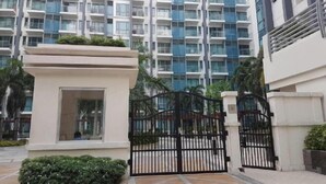Un edificio moderno con entrada protegida por un portón, un pequeño quiosco y un jardín bien cuidado.