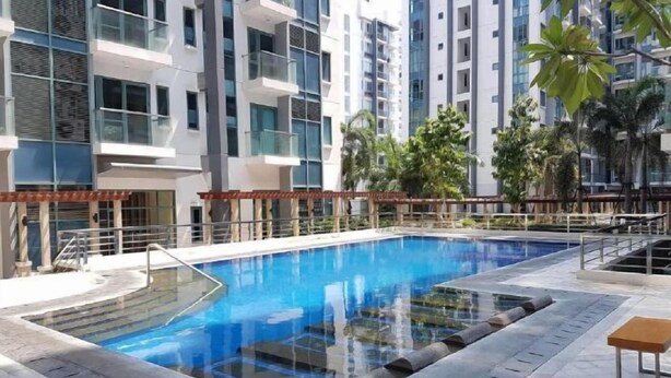 Una piscina rodeada de edificios modernos, con escalones que bajan a la piscina y una pequeña mesa cerca.