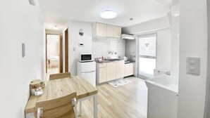 A modern kitchen with white cabinets, a wooden dining table, and a large window. - UenoMasakazuBuilding (Tokyo)