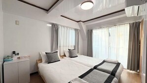 A hotel room with two beds, a small desk, and a window with curtains. - UenoMasakazuBuilding (Tokyo)