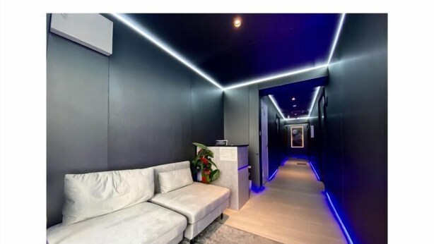 A modern hallway with a white sofa, a reception desk, and blue LED lighting. - UenoMasakazuBuilding (Tokyo)