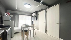 A compact kitchen with a dining area, a microwave, a clock, and a window with curtains. - UenoMasakazuBuilding (Tokyo)