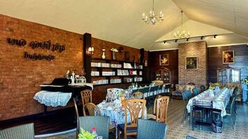 A restaurant with brick walls, tables set for dining, and a bookshelf in the background.