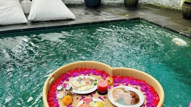 Un cadre agréable au bord de la piscine, avec un plateau flottant rempli de nourriture et de boissons, le tout entouré d’eau.