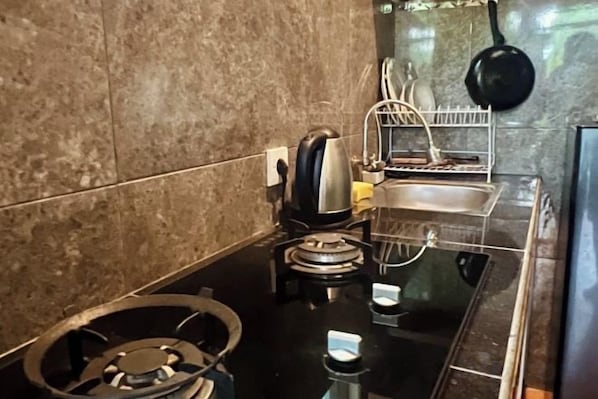 A kitchen with a gas stove, a coffee maker, and a hanging pot.