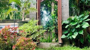 Un jardin agrémenté d’une arche en bois, d’une végétation luxuriante et de diverses plantes.