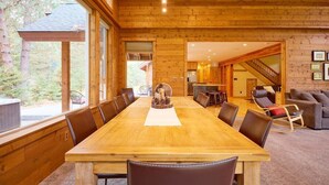 A wooden interior with a large dining table, chairs, a sofa, and a staircase leading to another room. - Mountain Lodge w/ Hot Tub + Private River Beach (Leavenworth)