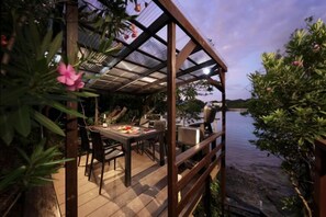 An outdoor dining area with a covered table and chairs, overlooking a body of water. - Crystal Villa Shirahama (Seaside) (Shirahama)