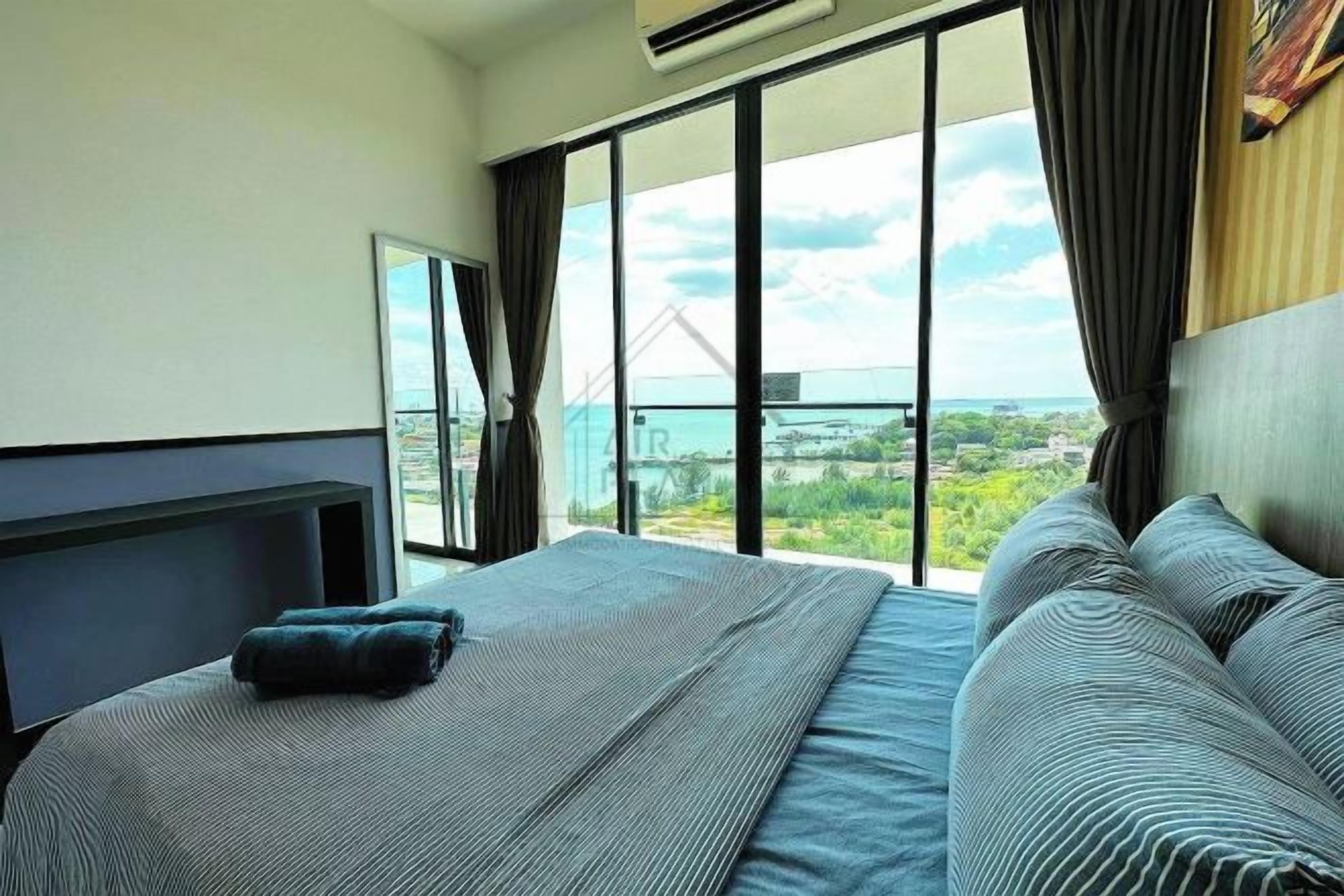 Ett hotellrum med en stor säng, utsikt över staden och en balkong.