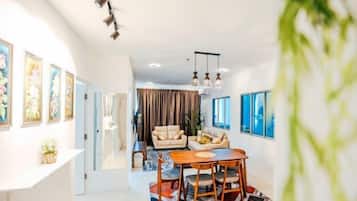 A modern living room with a dining area, a sofa set, and artwork on the walls.
