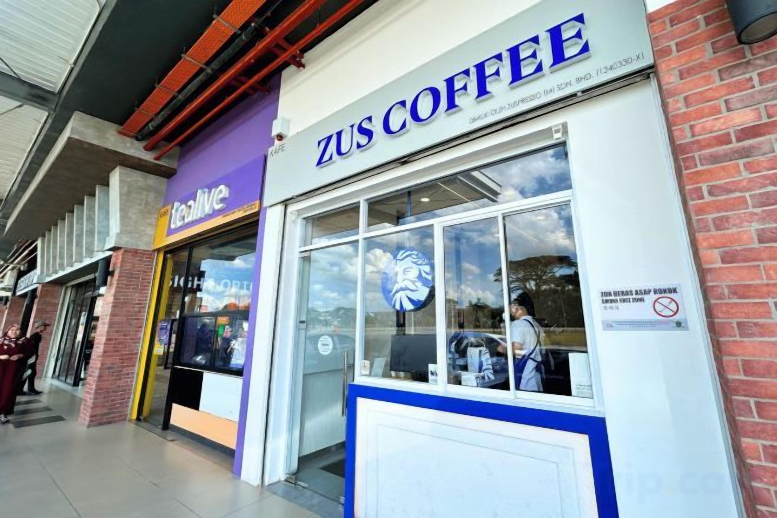 Una cafetería llamada ZUS COFFEE con un escaparate de vidrio y un letrero sobre la entrada.