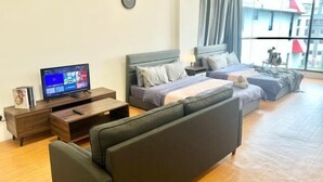 A modern hotel room with a bed, sofa, TV, and a large window offering a city view. - Sunway Geo Avenue Next to Medical Center Sunway University and Taylor University (Subang Jaya)