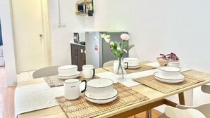 A dining table set with white plates and bowls, a vase with flowers, and a basket of fruits. - Sunway Geo Avenue Next to Medical Center Sunway University and Taylor University (Subang Jaya)