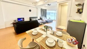 A modern living room with a dining area, a sofa, a TV, and a ceiling fan. - Sunway Geo Avenue Next to Medical Center Sunway University and Taylor University (Subang Jaya)
