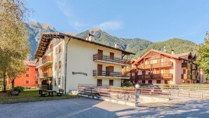A hotel with multiple balconies, a parking area, and a mountain backdrop.