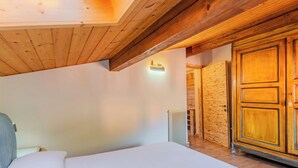 A bedroom with a wooden ceiling, a large bed, a wardrobe, and a radiator.