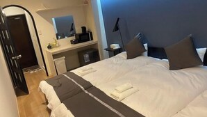 A hotel room with a bed, a desk, a chair, a mirror, and a nightstand. - TOUGAN HOTEL (Osaka)