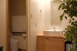 A bathroom with a toilet, a sink, and a cabinet. - TOUGAN HOTEL (Osaka)