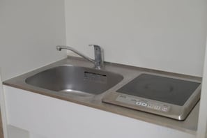 Cozinha com pia de aço inoxidável e fogão por indução embutido.