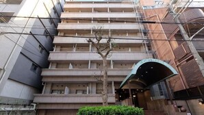 A multi-story building with a central staircase, a tree in front, and a covered entrance. - TOUGAN HOTEL (Osaka)