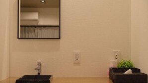 A bathroom with a sink, mirror, and two electrical outlets on the wall. - TOUGAN HOTEL (Osaka)