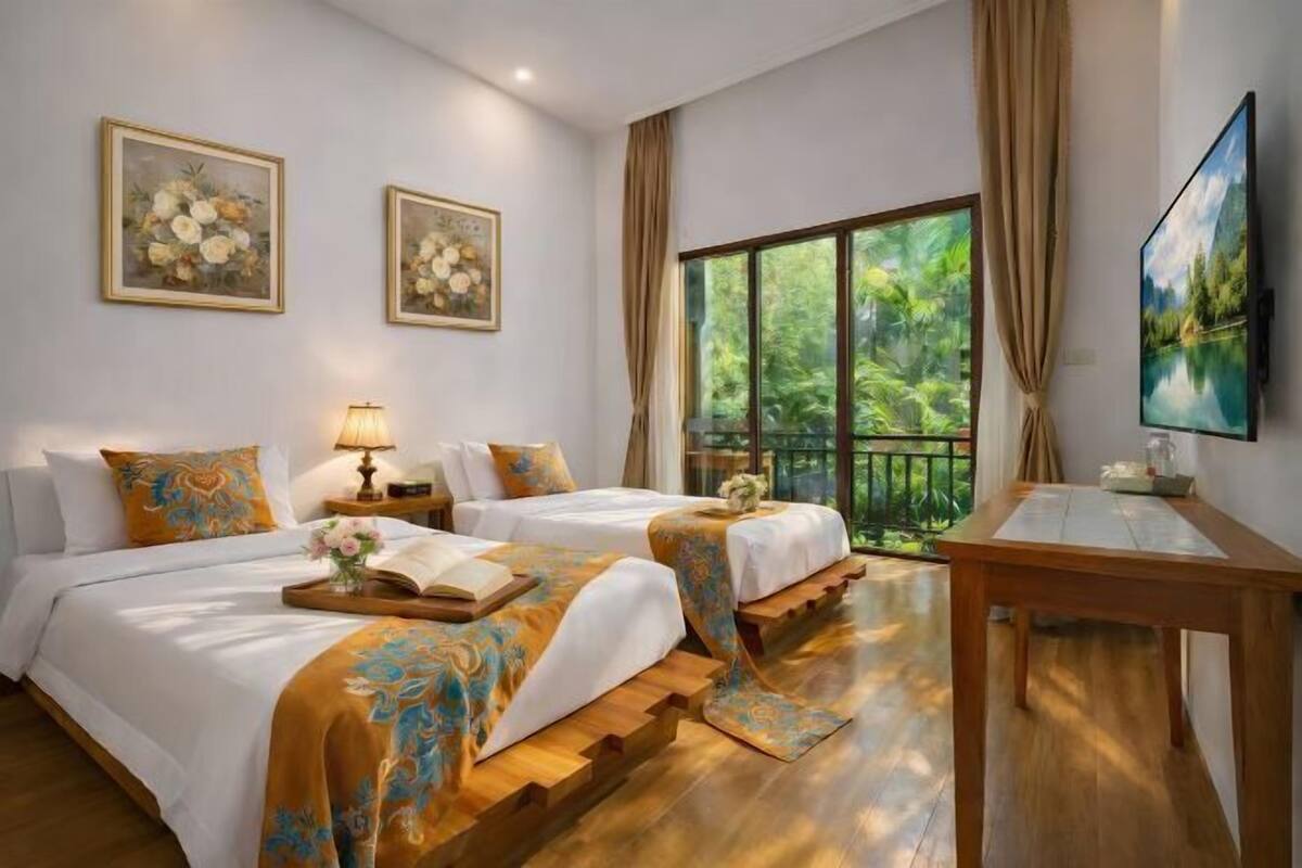 Habitación de hotel con dos camas, piso de madera, un ventanal con vistas a zonas verdes y un televisor en la pared.