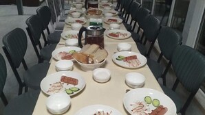 A long dining table with chairs, plates of food, and a coffee pot. - Central Asia Inn Hotel (Almaty)