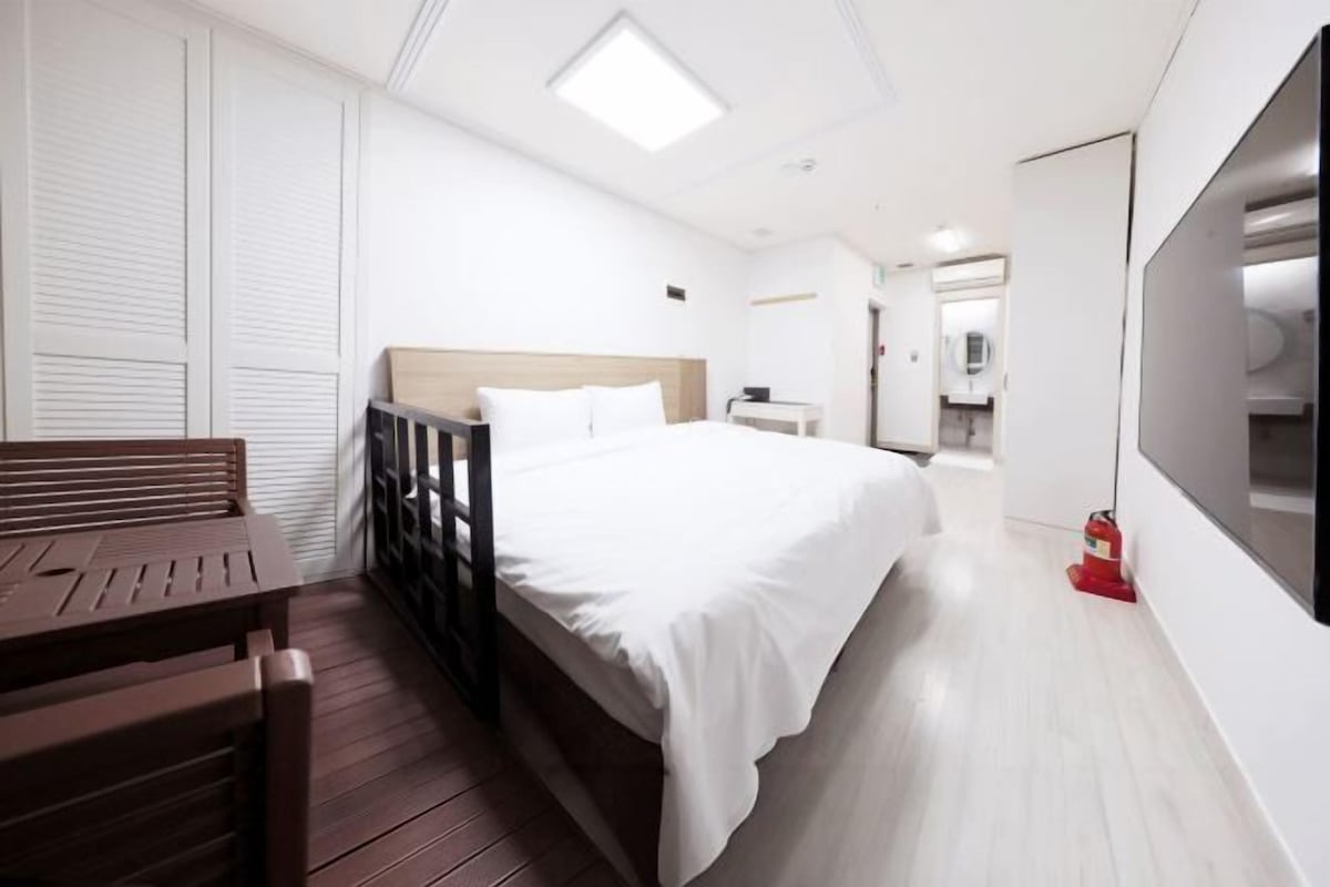 A modern hotel room with a wooden bed, a small desk, and a bench.
