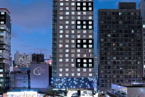 Un grand hôtel en hauteur, avec de nombreux étages et une grande enseigne à sa base.