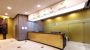 Een receptiebalie met een klok erboven, een bord met daarop Mandarin Gold Hotel, en een receptiegedeelte met een betegelde vloer.