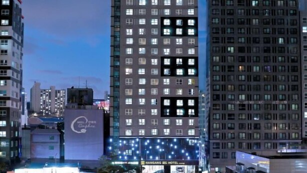 Een meerlaags hotel met een moderne gevel, verlichte ramen en een herkenbaar bord met de naam Hangang Hotel.