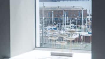 A marina with boats docked, a building in the background, and a window with a view of the marina.