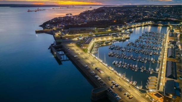 An aerial view of a marina with boats docked, a bridge, and a town in the background during sunset. - Harbour View - 2 Bedroom Apartment - Milford Haven (Milford Haven)