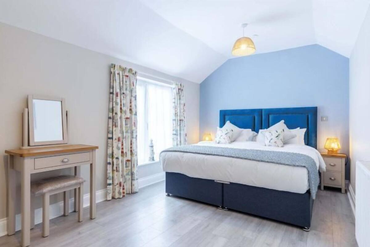 Ein Schlafzimmer mit einem Bett, Nachttischen, einem Schreibtisch und einem Stuhl.