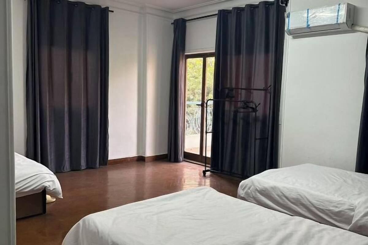 A room with two beds, a sliding glass door, and a ceiling fan.