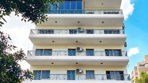 Un immeuble résidentiel à plusieurs étages, doté de balcons et de climatiseurs, avec un ciel dégagé.