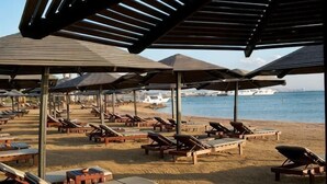 Ein Strand mit Liegestühlen und Sonnenschirmen.