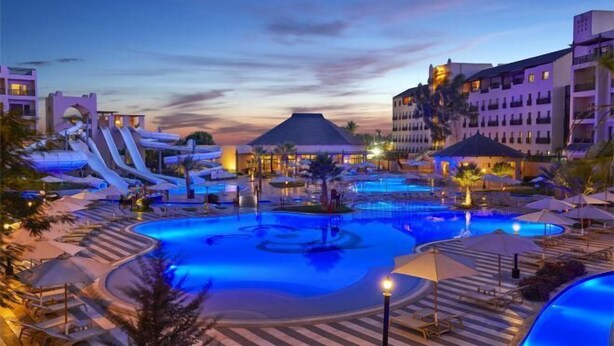 Ein Resort mit großem Pool, Wasserrutschen und einem Gebäude mit mehreren Balkonen.