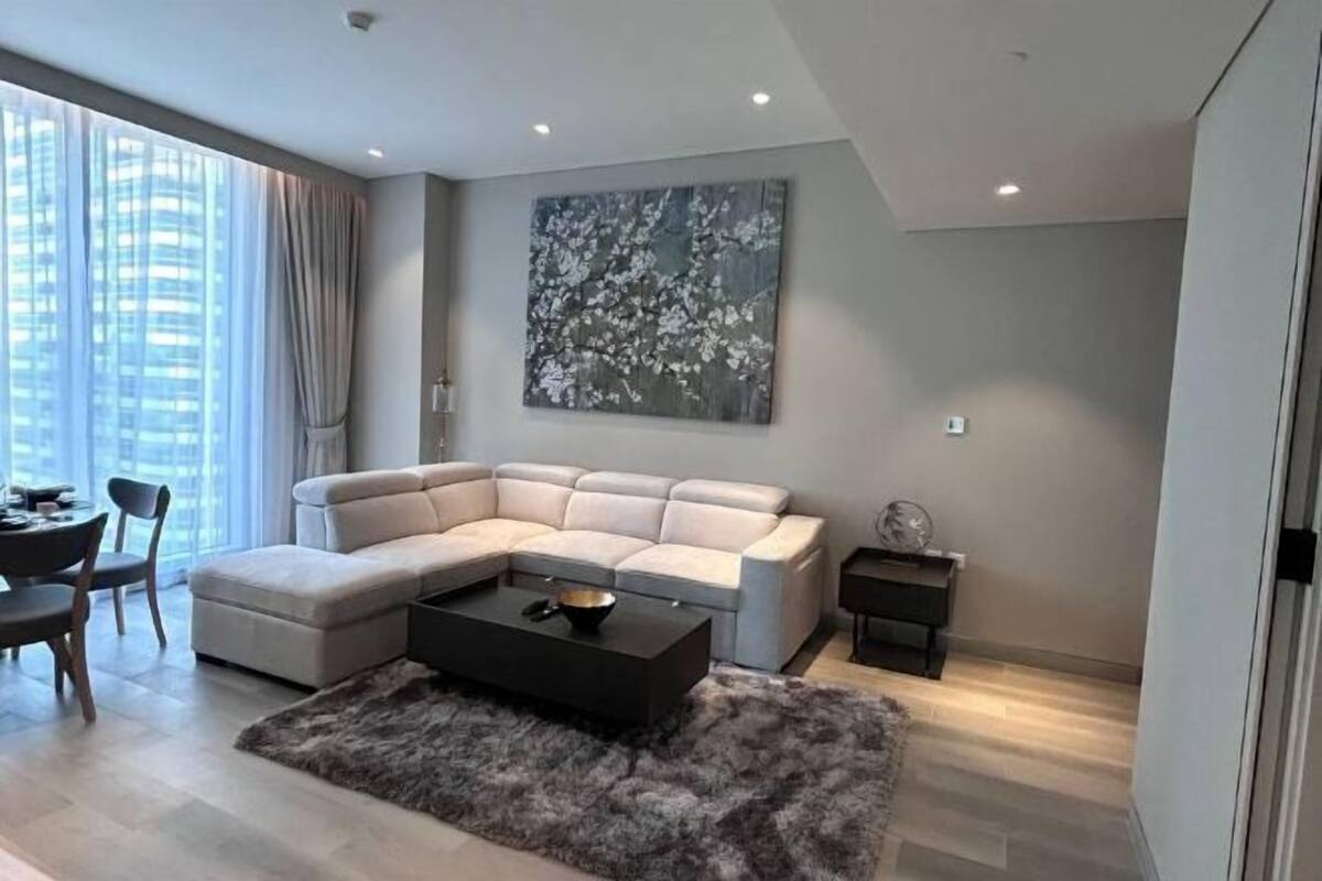 A modern living room with a sectional sofa, a coffee table, and a large abstract painting on the wall.