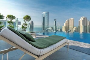 Zona de piscina en la azotea con una silla de descanso, cielo despejado y el perfil urbano al fondo.