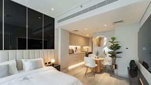 Una habitación de hotel moderna con una cama grande, un comedor y una cocina al fondo.