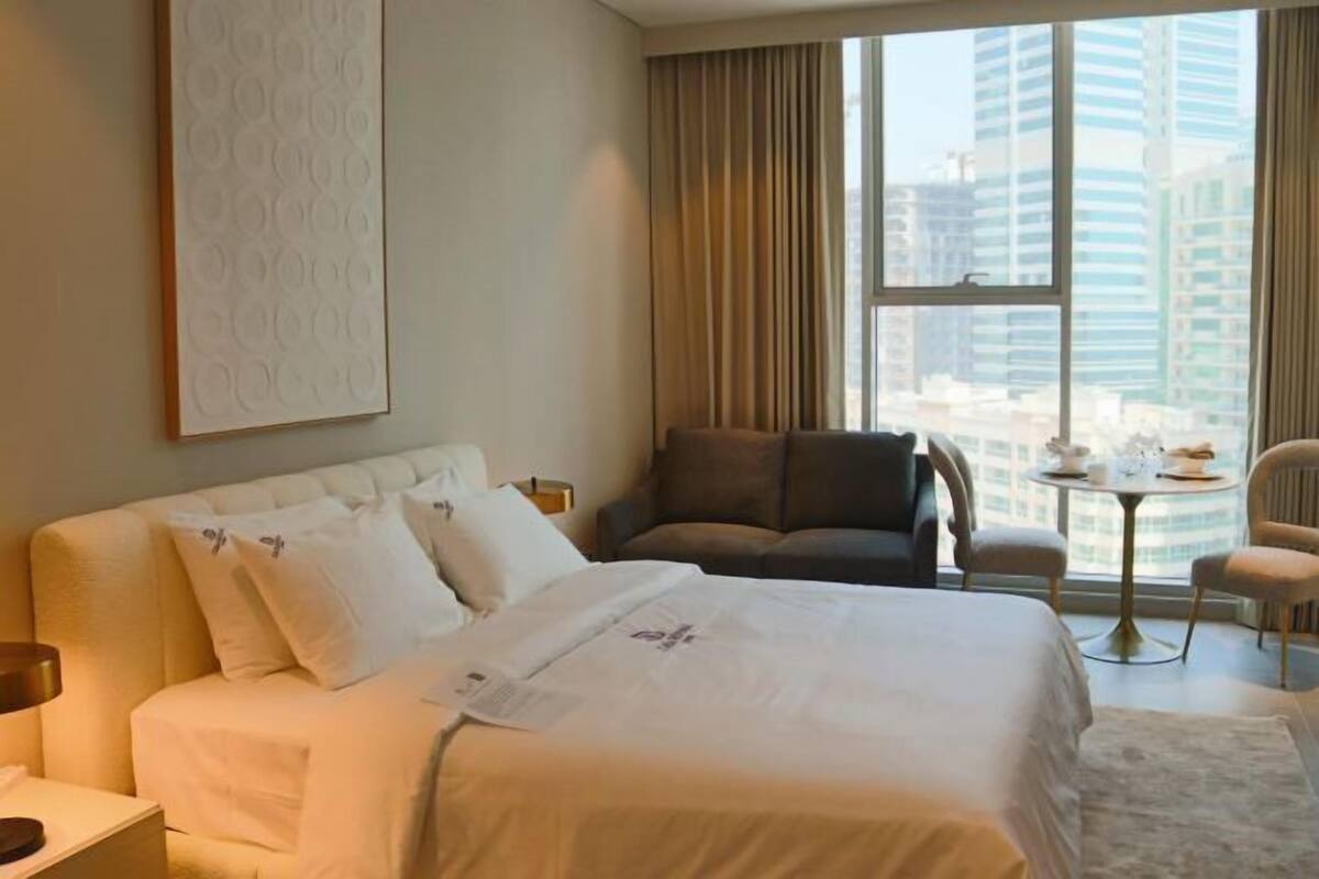 A hotel room with a large bed, a sofa, a chair, and a small table.