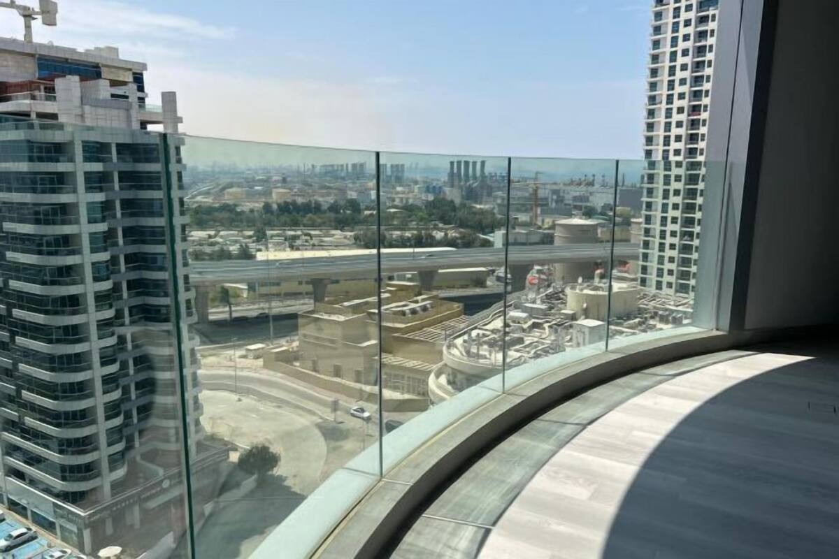 A high-rise building with a curved glass facade overlooking a cityscape.