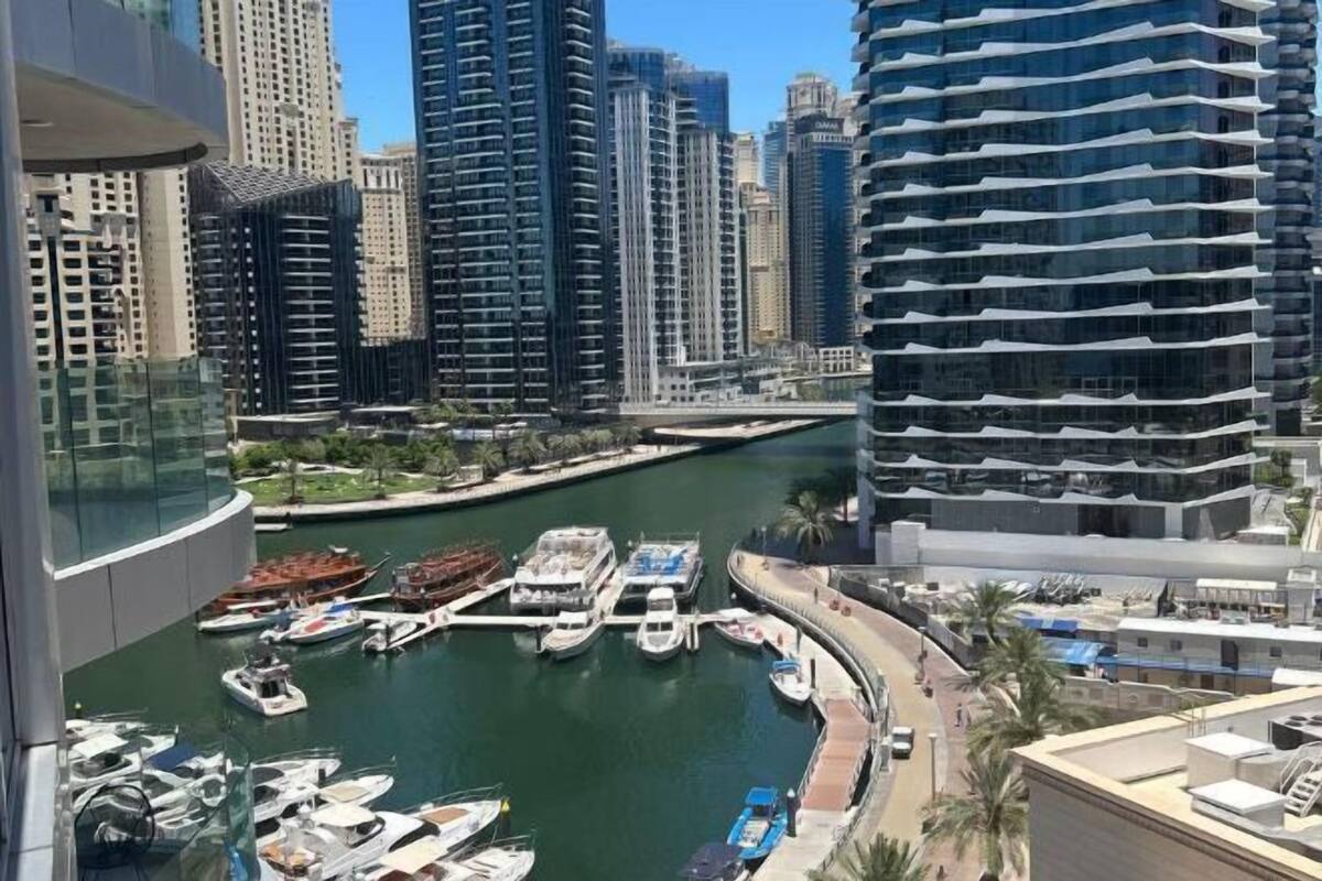 A marina with boats docked, surrounded by high-rise buildings.