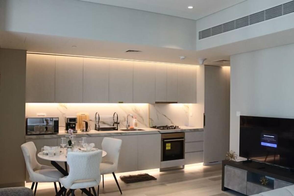 A modern kitchen with a dining area, built-in appliances, and a flat-screen TV.